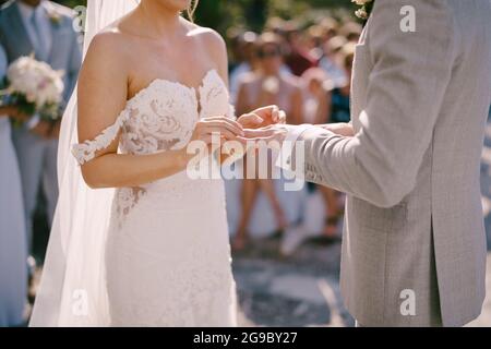 Sposa mette l'anello sulla mano dello sposo Foto Stock