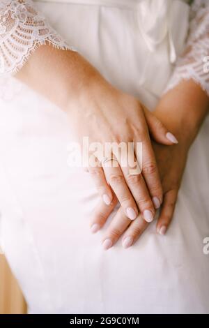 Sposa in abito bianco ha piegato le mani in grembo Foto Stock