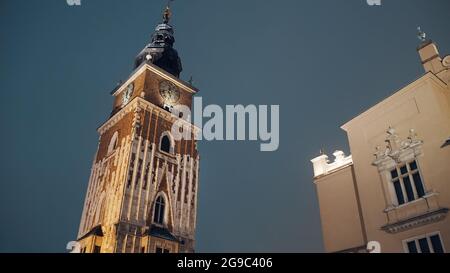 Cracovia, Polonia 03.02.2021 Vista a basso angolo del campanile con orologio nella piazza principale del mercato Cracovia, Polonia. Notte. Città vecchia con architettura antica durante la notte. Torre dell'Orologio nella piazza principale del mercato. Foto Stock