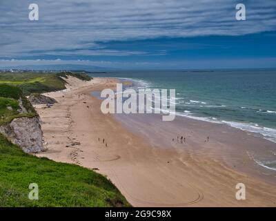 La sabbia incontaminata di Whiterocks Beach e le scogliere costiere sulla costa di Antrim Causeway, nell'Irlanda del Nord, Regno Unito. Preso in una giornata di sole in estate con il lig Foto Stock