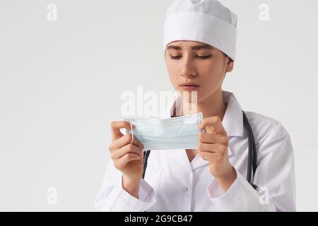 Ritratto di giovane medico femminile indossare la maschera facciale medica protettiva su sfondo bianco, spazio copia Foto Stock