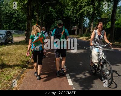 22 luglio 2021, Nijmegen, Paesi Bassi: I partecipanti camminano davanti a una signora che cavalca una bicicletta durante l'evento. Il Vierdaagse, conosciuto anche come le Marche internazionali di quattro giorni, il più grande evento a piedi di più giorni del mondo che si celebrerebbe ogni anno, ma a causa della situazione sanitaria attuale, per il secondo anno consecutivo, l'evento è stato annullato. Tuttavia, il KWBN (Koninklijke Wandel Bond Nederland) ha organizzato il 'Vierdaagse alternativo', a cui tutti potevano unirsi, scegliendo una distanza tra 10 e 50 km, e un percorso da qualche parte nei Paesi Bassi. Partecipazione alla quattro giorni alternativa Foto Stock