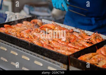 Chef che cucinano gamberi rossi di langoutine freschi, gamberi alla griglia a cibo locale estivo Foto Stock