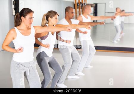 Gruppo di persone che praticano movimenti di autodifesa in sala di formazione Foto Stock