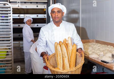 Panettiere ispanico che mostra baguette appena sfornate in panetteria Foto Stock