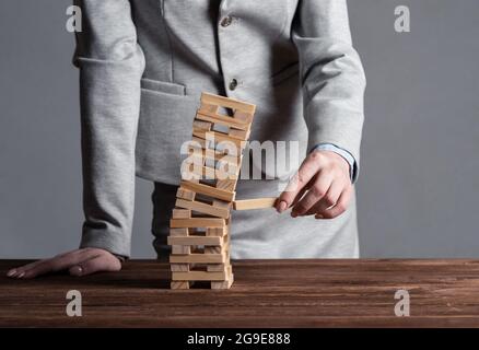 Uomo d'affari che rimuove il blocco di legno dalla torre Foto Stock