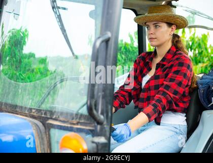 Giovane agricoltore specializzato che lavora su un trattore piccolo in frutteto Foto Stock