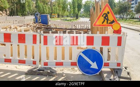 La barriera protettiva in plastica recinzioni il luogo di lavoro stradale. Recinzione in plastica rossa e bianca vicino al sito di riparazione stradale. Lavori di costruzione sulla strada, roa Foto Stock