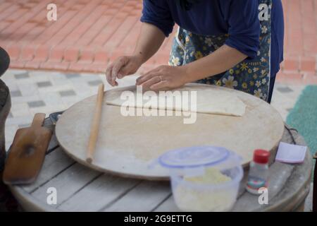 cibo di strada: pancake. donna locale cuoce pancakes su lamiera, in cui mette formaggio, spinaci, o patate. Focalizzazione selettiva. Foto Stock