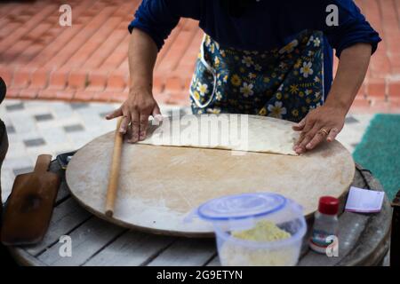 cibo di strada: pancake. donna locale cuoce pancakes su lamiera, in cui mette formaggio, spinaci, o patate. Focalizzazione selettiva. Foto Stock