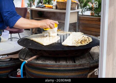 cibo di strada: pancake. donna locale cuoce pancakes su lamiera, in cui mette formaggio, spinaci, o patate. Focalizzazione selettiva. Foto Stock