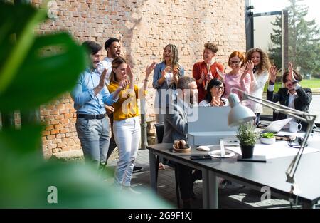 Gruppo di imprenditori eccitati che lavorano al progetto indoor in ufficio, celebrando il contratto di successo. Foto Stock