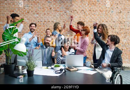 Gruppo di imprenditori eccitati che lavorano al progetto indoor in ufficio, celebrando il contratto di successo. Foto Stock