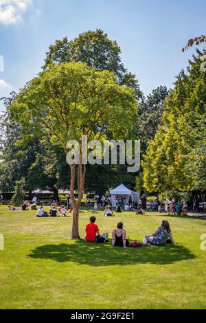 Gruppo di persone prendono ombra sotto un albero durante la Worcester's Band nel festival del parco, estate 2021 Foto Stock