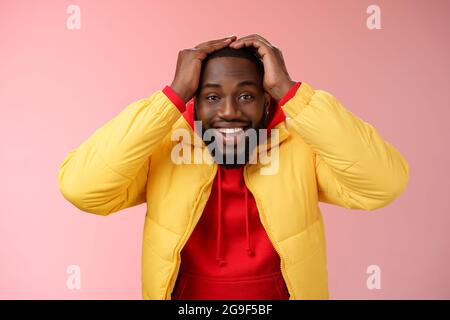 Vita-up sorpreso felice fortunato giovane afroamericano sopportato maschio in giallo giacca che tiene le mani testa sorridente impressionato gioiosamente ricevere impressionante Foto Stock