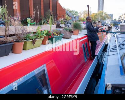 Un uomo nero su una barca stretta lungo il canale del Rent a Little Venice, Londra Foto Stock