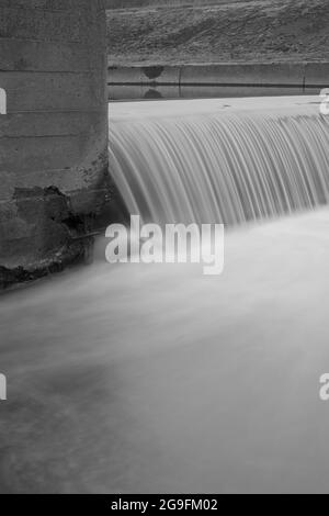 Cascata artificiale in un canale di cemento cittadino. Fotografia in bianco e nero a lunga esposizione. Foto Stock