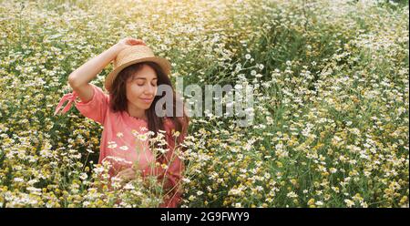 Bella donna godendo Daisy campo, bella femmina in prato di fiori banner. Bella ragazza rilassante all'aperto, divertirsi, tenere pianta, felice giovane Foto Stock