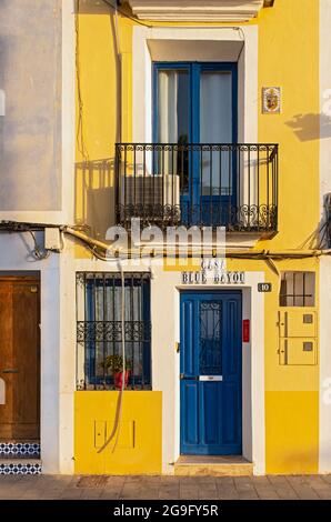 Primo piano di una porta blu e di un balcone di case di pescatori gialle a Villajoyosa, Spagna Foto Stock