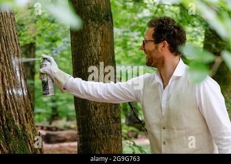 Mittelangeln, Germania. 26 luglio 2021. Jan Philipp Albrecht (Bündnis 90/Die Grünen), ministro Schleswig-Holstein per la transizione energetica, l'agricoltura, l'ambiente, la natura e la digitalizzazione, segna l'albero degli habitat del 80000. Gli alberi sono indispensabili per la conservazione e la promozione della biodiversità e la conservazione della natura delle foreste integrative, hanno spiegato i rappresentanti delle foreste statali dello Schleswig-Holstein in occasione di un evento stampa. Credit: Frank Molter/dpa/Alamy Live News Foto Stock