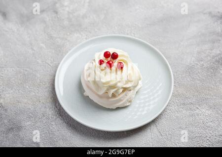 Mini pavlova su piatto su fondo grigio pietra con frutti di bosco e panna montata Foto Stock