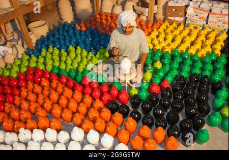 Un vasaio al lavoro che mette i ritocchi finali ad una banca di piccini e circondato da decine di banche di piccini già fatto, in Bahrain, il Medio Oriente Foto Stock