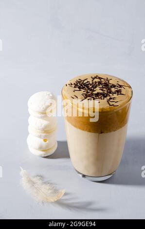 Caffè Dalgon in un bicchiere alto con schiuma e gocce di cioccolato su sfondo grigio Foto Stock
