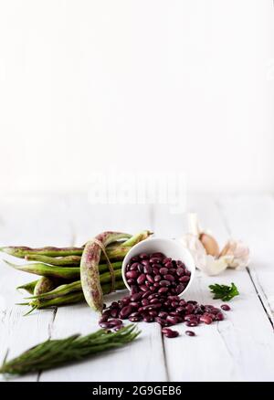 Fagioli rossi fagioli fagioli su uno sfondo di legno bianco. Cibo vegetariano ricco di proteine con spazio di copia Foto Stock