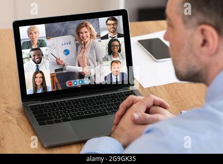 Videoconferenza. Uomo d'affari seduto al portatile durante il meeting aziendale online in ufficio. Multiculturale Business People comunicare con il Gruppo VI Foto Stock