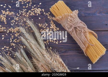 Mazzo di spaghetti con spaghetti di grano e grani su fondo scuro. Foto Stock