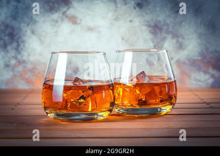 Due bicchieri di whisky con ghiaccio. Vita morta. Brandy, borbone su un tavolo di legno marrone. Bevanda alcolica forte. Rum, scotch Foto Stock