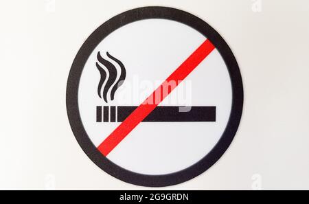 Cartello rotondo rosso e nero per non fumatori, adesivo in un luogo pubblico su sfondo bianco. Foto Stock