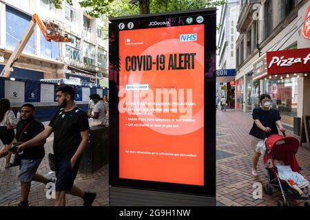 Si passa un nuovo Covid-19 Alert Public Health England, NHS Information Board su New Street in quella che è stata un'atmosfera positiva nel tanto atteso giorno della libertà, quando tutte le restanti restrizioni del coronavirus sono revocate nel Regno Unito il 19 luglio 2021 a Birmingham, Regno Unito. Mentre molte persone indossano maschere facciali, non sono più obbligatorie, mentre i consigli del governo suggeriscono che si consiglia di indossare una copertura facciale in luoghi pubblici occupati all'interno e durante il trasporto. Foto Stock