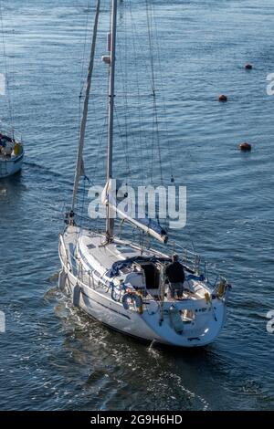 grande yacht da crociera offshore che entra in un porto con un uomo di mezza età al timone. grande yacht da crociera che entra in porto. Foto Stock