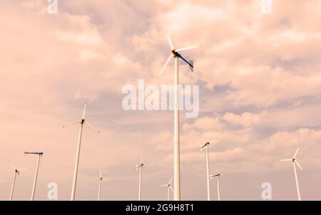 Paesaggio di un mulino a vento a turbina eolica o parco eolico la mattina d'estate. Spettacolari nuvole sul cielo del tramonto sullo sfondo. Concetto di energia pulita. Foto Stock