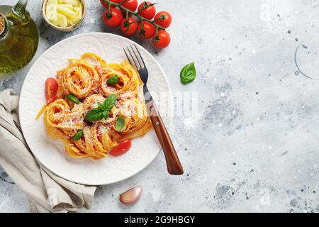 Gustosa e appetitosa classica tagliatelle italiana con salsa di pomodoro, parmigiano e basilico su piatto su tavolo leggero. Vista dall'alto, orizzontale Foto Stock