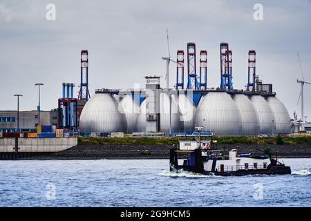 Amburgo, Germania, 22 luglio 2021: Digestori di un impianto di depurazione delle acque reflue di Amburgo sull'Elba con un traghetto in primo piano sul riv Foto Stock