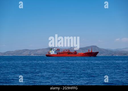 Nave petroliera chimica, nave di colore rosso che trasporta in liquidi chimici alla rinfusa, approvvigionamento delle isole greche delle Cicladi, mare blu dell'Egeo e cielo trasparente Foto Stock