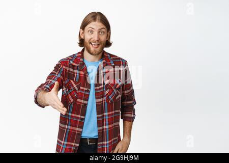 Piacere di conoscerti. Uomo biondo sorridente che allunga la mano per agitare la mano, scuotendo le mani con te, salutando qualcuno, saluta, in piedi Foto Stock