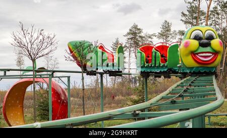 Ucraina, Kiev - 24 ottobre 2019: Attrazione tipo montagne russe. Treno a ruote russe a forma di Caterpillar in un parco divertimenti. Giostre e tempo libero Foto Stock