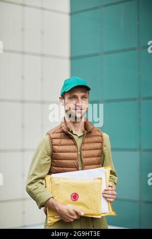 Verticale vita su ritratto di uomo di consegna tenendo pacchi e sorridente, copia spazio Foto Stock