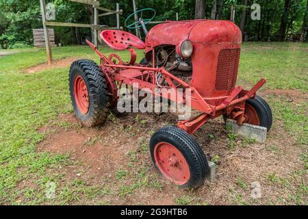 Antico piccolo trattore rosso fattoria parcheggiato nel campo in una fattoria per la visualizzazione all'aperto angolo vista primo piano Foto Stock