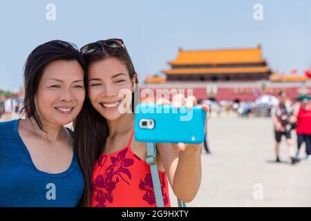 Madre figlia turisti che prendono selfie di vacanza di viaggio a Piazza Tiananmen Pechino, Cina, Asia. Donne sorridenti che scattano foto insieme a Famous Foto Stock