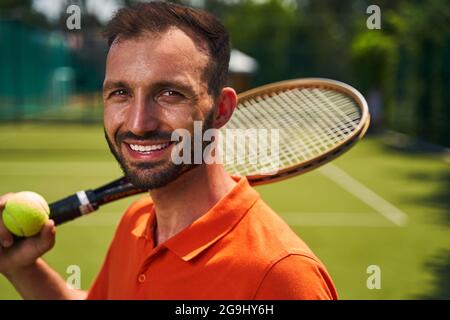 Bel giocatore di tennis maschile ad alta spirale in posa per la macchina fotografica Foto Stock