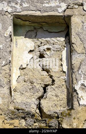 Grande spaccatura su parete grigia di vecchio edificio dilapidato, immagine astratta di spaccatura verticale, dettaglio. Nicchia rettangolare in Wall. Conseguenze di terremoto Foto Stock
