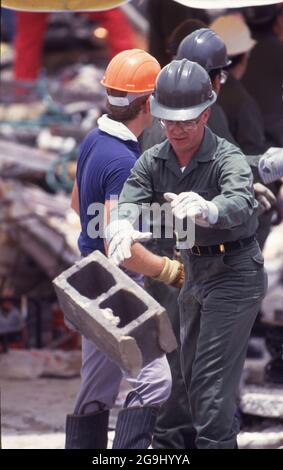 Brownsville Texas USA, luglio 8,1988: Volontari soccorritori pettinare le macerie del negozio Amigo nel centro di Brownsville. Le forti piogge hanno causato il crollo dell'edificio, uccidendo 14 persone. Gli ingegneri hanno individuato una costruzione difettosa su un'aggiunta di terzo piano come la causa del crollo. ©Bob Daemmrich Foto Stock