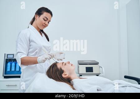 Cosmetologo competente che fa la procedura di bellezza in salone Foto Stock