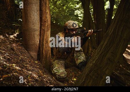 Soldato seduto e in possesso di armi da fuoco per sparare Foto Stock