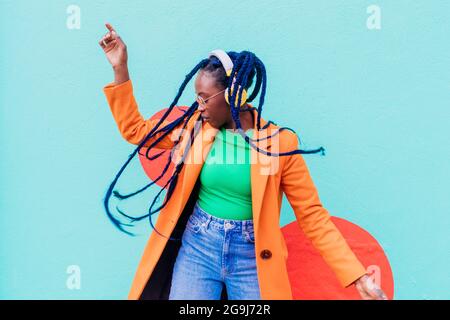 Italia, Milano, donna elegante con cuffie che ballano contro il muro Foto Stock