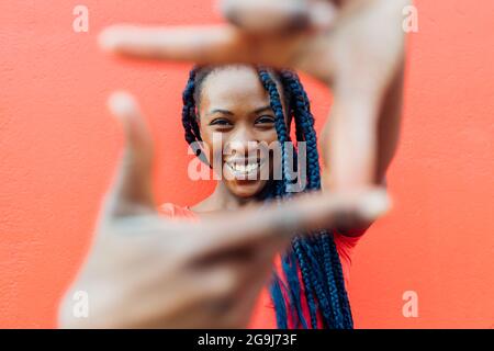 Italia, Milano, Ritratto di giovane donna con trecce che fanno cornice dita Foto Stock